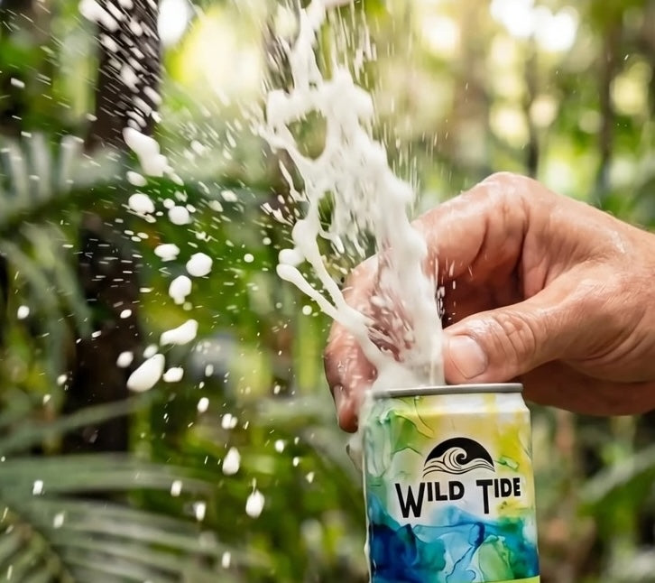Person opening a can of Wild Tide Original flavored ginger beer with a natural background