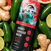 A can of Wild Tide Grapefruit Jalapeño ginger beer laying down in a pile of jalapeños, slices of grapefruit and lime, and pieces of ginger.