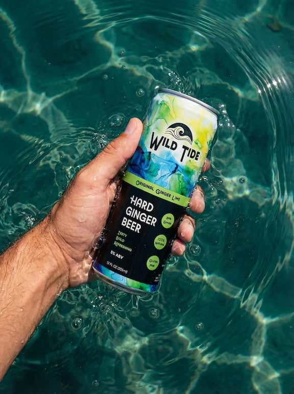 A can of Original Ginger Lime ginger beer held by a guy's hand in the pool.