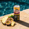 A can of Wild Tide Pineapple Passionfruit on the side of a pool with tropical fruits next to it.