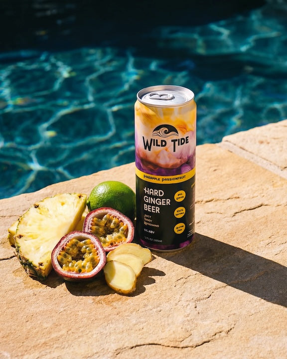 A can of Wild Tide Pineapple Passionfruit on the side of a pool with tropical fruits next to it.
