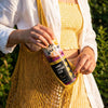 Woman in a yellow shirt and shorts and a white cover top holds a yellow sling bag pulling out a can of Wild Tide Pineapple Passionfruit ginger beer.