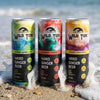 Three cans of Wild Tide hard ginger beer on the beach with a wave hitting them from the back.